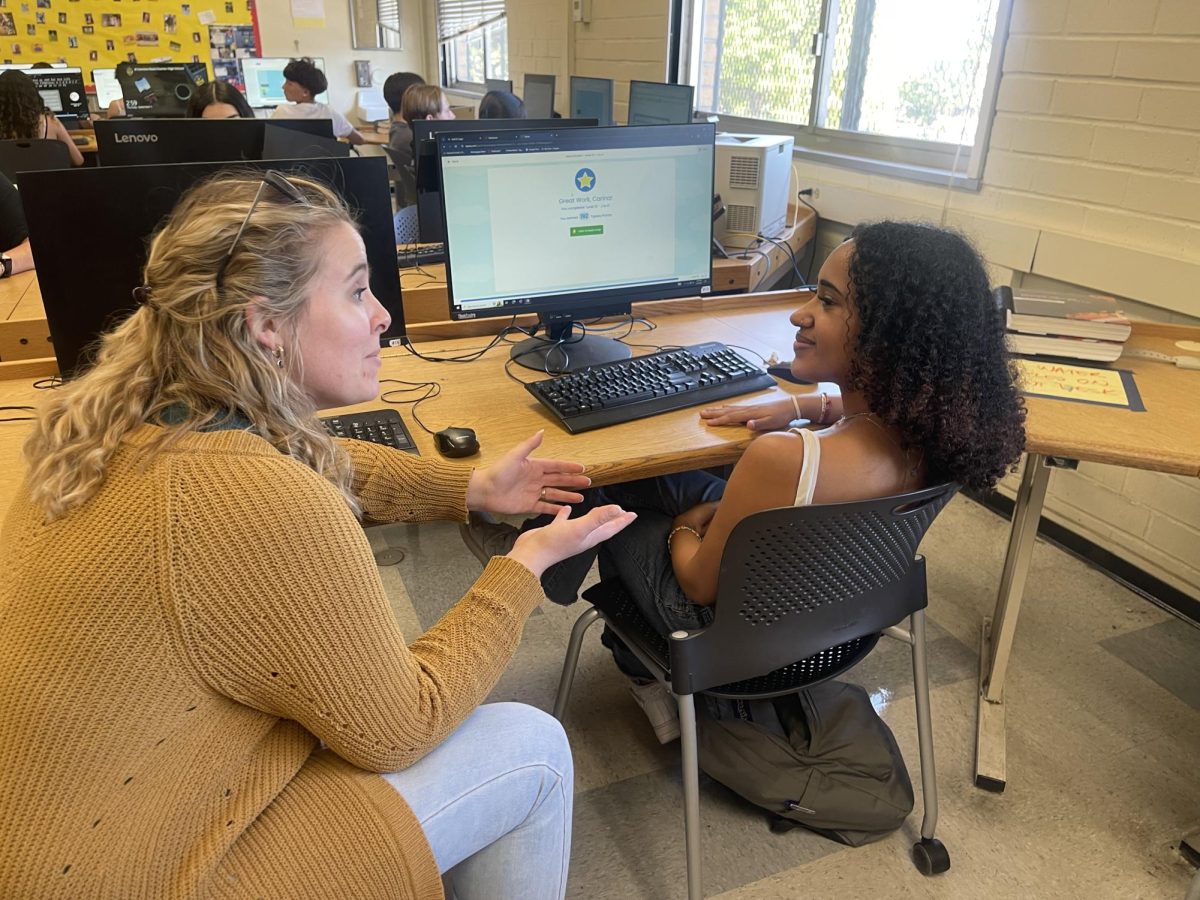 Ms. Rayzor speaks with a student during class